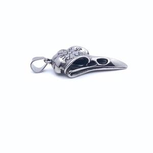 Vue macro d'un pendentif crâne de corbeau en argent vieilli avec boussole viking