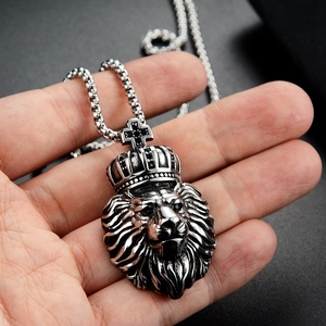 Détail d'un pendentif tête de lion rétro avec couronne tenu à la main pour l'échelle