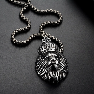 Vue macro du pendentif tête de lion avec couronne et pierres noires sur chaîne box