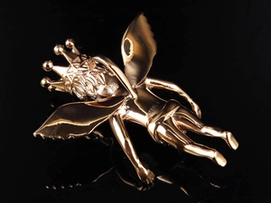 Macro shot of gold angel pendant showing detailed wings and STEEL X engraving on back