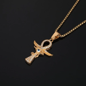 Golden Ankh necklace with Eye of Horus wings and crystal stones on a polished black surface