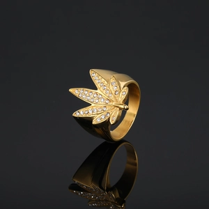 Bague feuille d'érable dorée style hip hop avec cristaux sur une surface noire réfléchissante