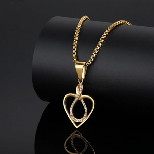 Golden heart pendant necklace with infinity symbol on a black display stand