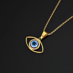 Golden Evil Eye pendant necklace with blue center and crystals on a black mirror surface