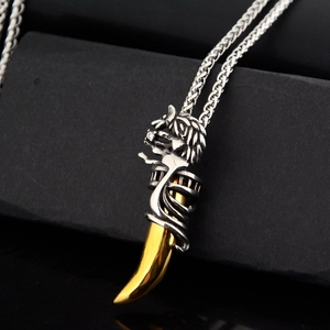 Détail du pendentif dent de loup dorée avec dragon argenté sur une chaîne de blé robuste