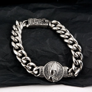 Silver Cuban link bracelet with prayer hand pendant and vintage pattern on black background