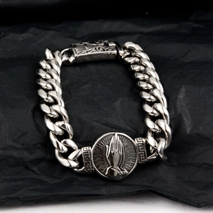Detailed macro view of retro Cuban link bracelet with prayer hands medal and floral clasp