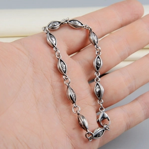 Macro detail of retro evil eye link bracelet with embossed sun patterns and aged silver finish