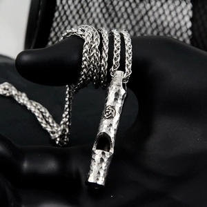 Detail of vintage silver whistle pendant with hammered texture and Celtic knot engraving