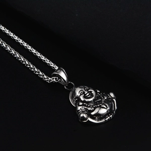Vue macro d'un pendentif bouddha en acier inoxydable sur une chaîne épi avec fond noir