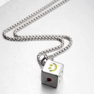 Macro view of steel necklace with a dice cube pendant and a yellow smiley face