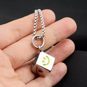 Close-up of dice pendant necklace with yellow smiley face and red dots on box chain
