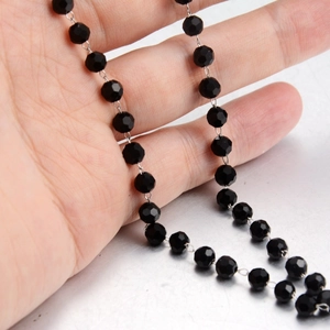 Detailed close-up of faceted black beads connected by silver links on a chain