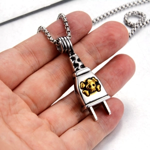 Macro shot of a dual-tone silver and gold skull plug pendant with a box chain