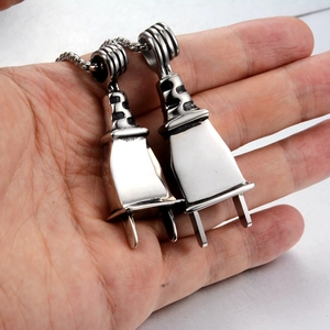 Detail shot of two polished stainless steel skull plug pendants held in hand
