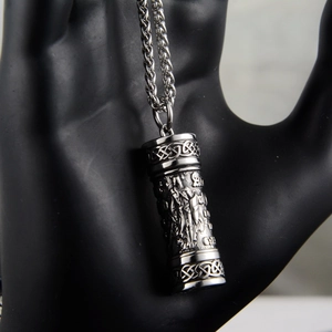 Close-up of cylinder pendant necklace with Celtic knot patterns on a black hand model