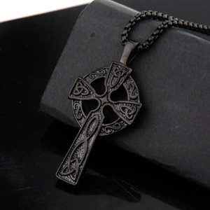 Close-up of vintage black Celtic cross pendant with intricate knotted steel texture