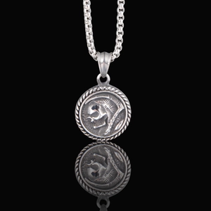Close-up of vintage Gothic skull coin pendant with silver chain and reflection on black