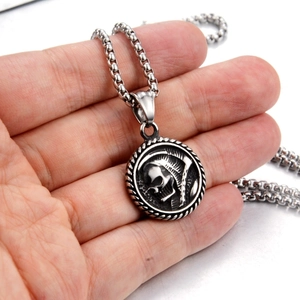 Detailed macro view of Gothic skull and scythe relief on a vintage steel round pendant