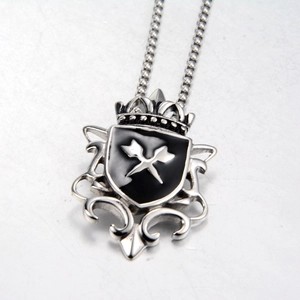 Macro detail of silver shield pendant with black enamel cross swords and crown design