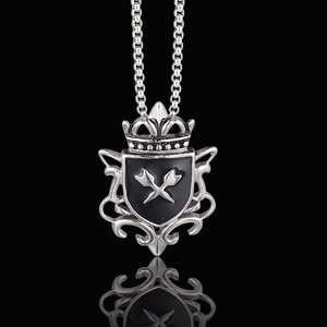 Detail of vintage gothic shield pendant with silver crown and cross on black background