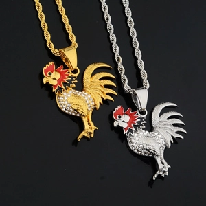 Detail of rooster pendant necklace in gold and silver with white rhinestones and red enamel