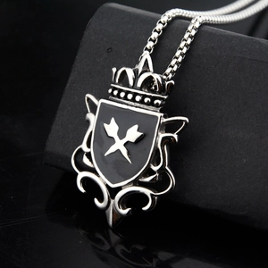 Macro shot of gothic shield pendant with crown and crossed arrows on black textured stand