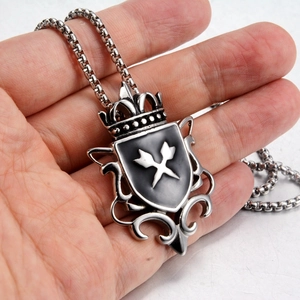 Detailed view of silver shield pendant with crown crest and black enamel on ball chain