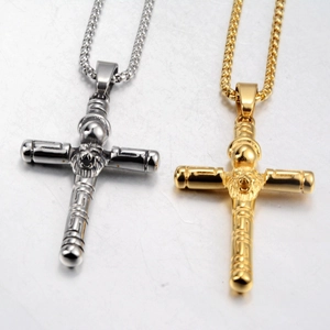 Dettaglio dei ciondoli a croce oro e argento con testa di leone e greca ornamentale