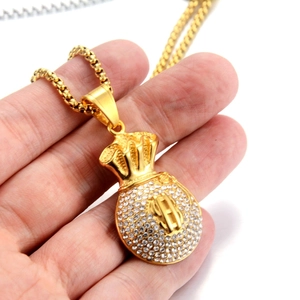 Close-up of golden money bag pendant with dollar sign and rhinestones held in hand