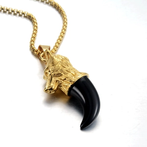 Vue détaillée du pendentif tête de loup dorée avec dent noire et chaîne à maillons