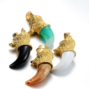 Détail de pendentifs crocs de loup en noir, vert et blanc avec monture en métal doré