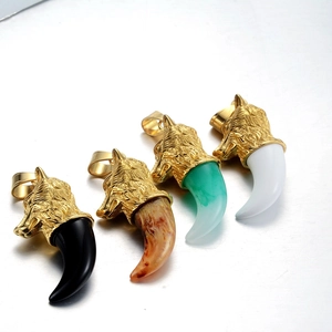 Détail de quatre pendentifs dents de loup noirs, bruns, verts et blancs avec gravures dorées