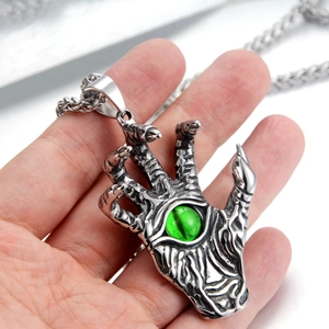 Detailed macro shot of punk style evil eye devil claw pendant with green gemstone