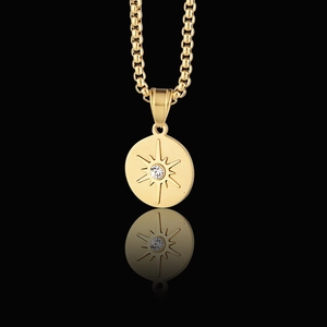 Polished gold sun and star pendant necklace with central zircon on black background
