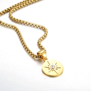 Detailed close-up of a golden coin pendant with a sparkling starburst zircon and box chain