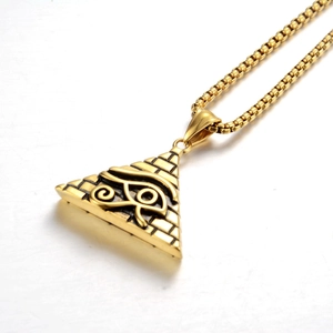 Macro shot of gold pyramid pendant with Eye of Horus relief and polished box chain link