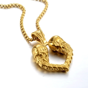Detalle de un colgante de corazón dorado formado por dos calaveras en una cadena box