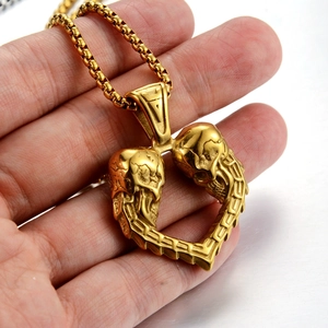 Primer plano del colgante de calavera de corazón dorado con cadena de caja gruesa