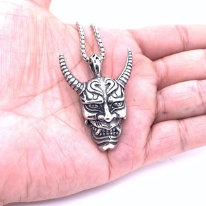 Hannya mask pendant necklace in silver stainless steel held in hand for scale