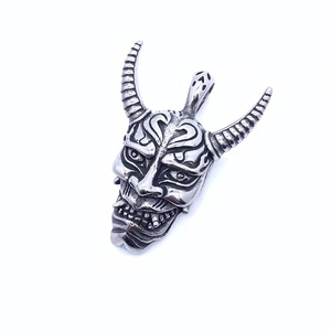 Detailed macro view of vintage titanium steel Hannya mask pendant with oxidized finish