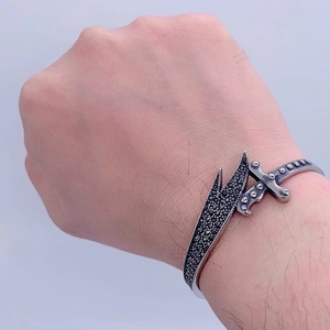 Macro detail of vintage sword-shaped bangle with micro-paved black stones on men's wrist