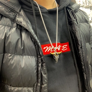 Détail du collier tête de taureau avec cornes dorées et pierre noire sur un sweat