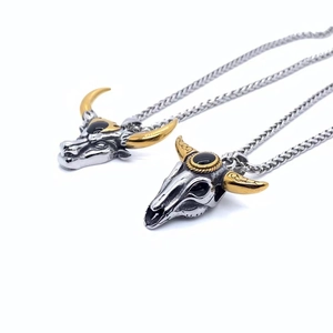 Vue détaillée des pendentifs tête de taureau bicolores avec cornes dorées et pierres noires