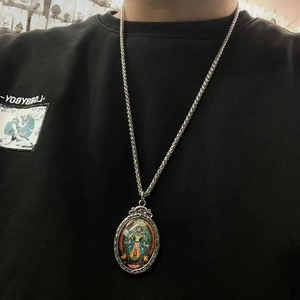 Ethnic oval Thangka pendant necklace in titanium steel with wheat chain on a black hoodie