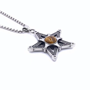 Détail macro du pendentif pentagramme avec pierre œil de tigre brun et acier vintage