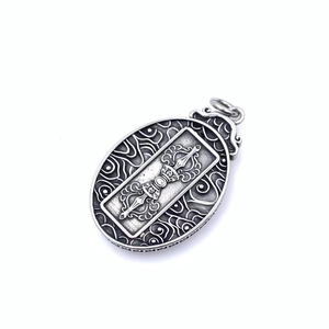 Macro shot of oval Thangka pendant with Vajra pattern and ethnic vintage engraving