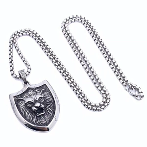 Detalle del colgante de escudo con cabeza de león vintage y cadena de acero tipo box