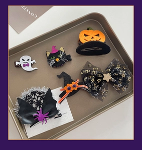 Close-up of Halloween hair clip set featuring ghosts, pumpkins, and witch hats on a metal tray