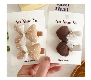 Détail de barrettes faites main avec nœuds et fraises sur carte de présentation